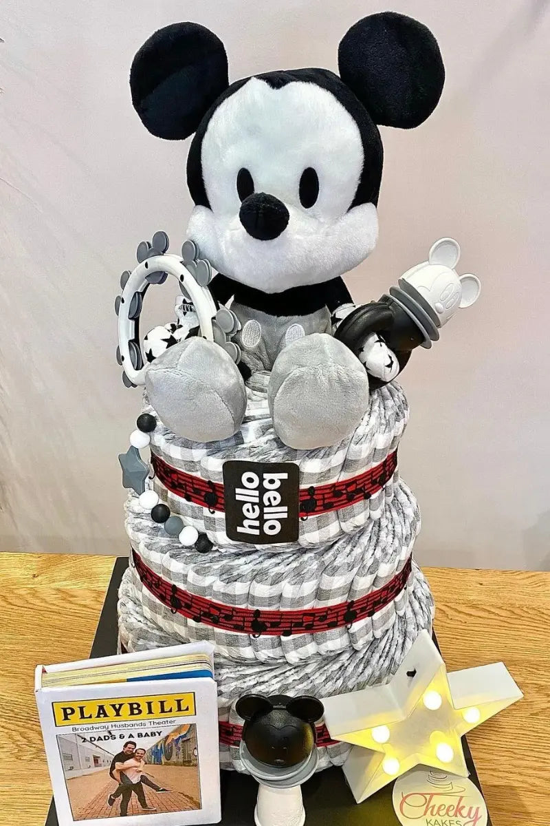 Baby shower diaper cake with a Mickey Mouse theme, featuring a plush toy and accessories