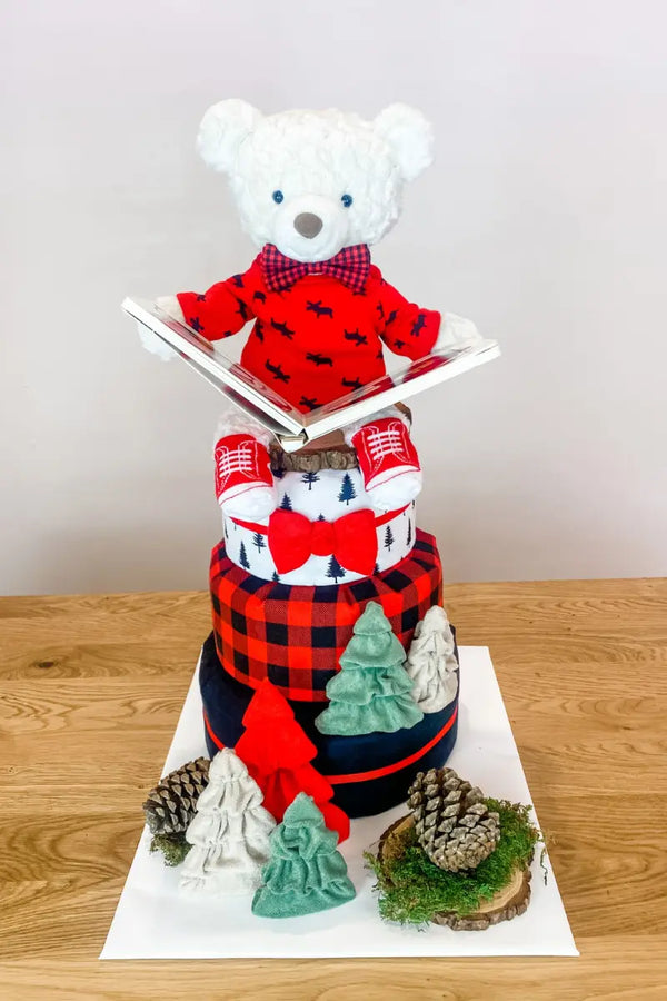 Plaid-themed diaper cake with a bear reading a book, adorned with festive decorations, perfect as a holiday diaper gift.
