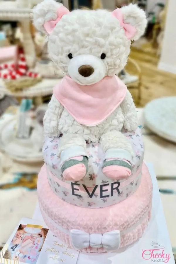Signature diaper cakes featuring plush animals, soft pastel fabrics, and personalized baby name designs.